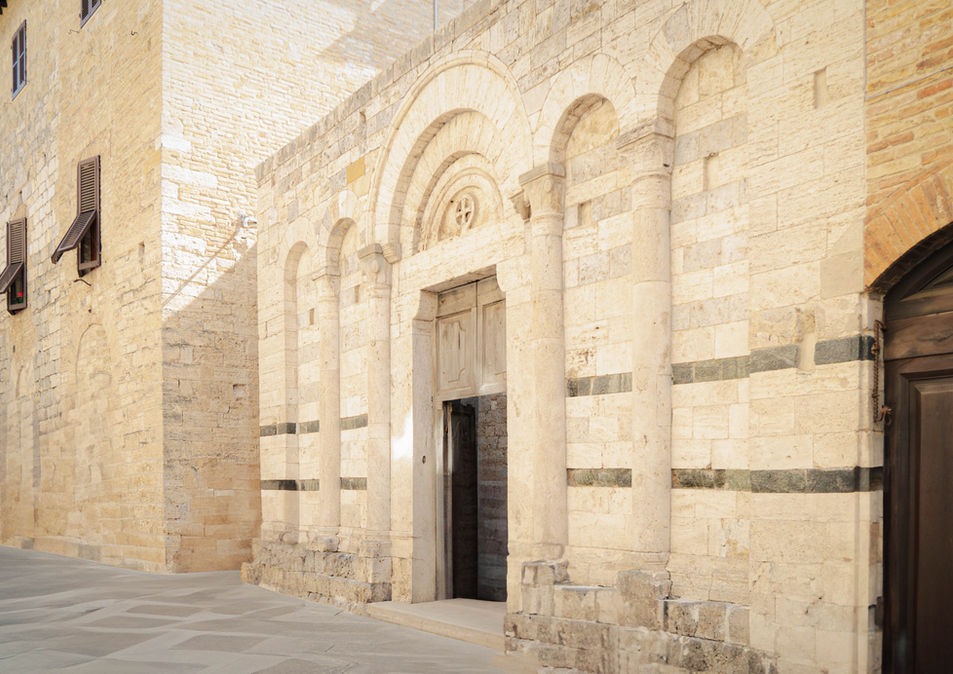 Historic stone building with arched facade and wooden entrance photographed by Jean Banzhoff