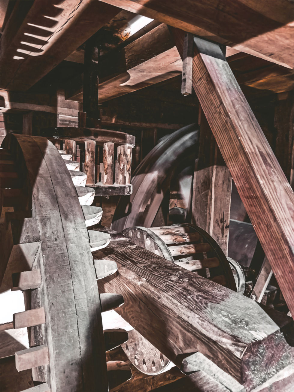 Close-up of a historic wooden gear system with interlocking teeth, heavy beams, and aged surfaces; part of a mill mechanism in Harpers Ferry, showcasing early industrial craftsmanship and mechanical design.