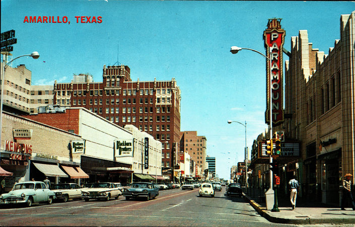 A vintage postcard with a photograph of a wide street lined with buildings