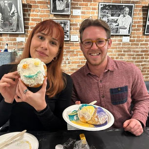 Two guests smile and hold up decorated king cake challahs