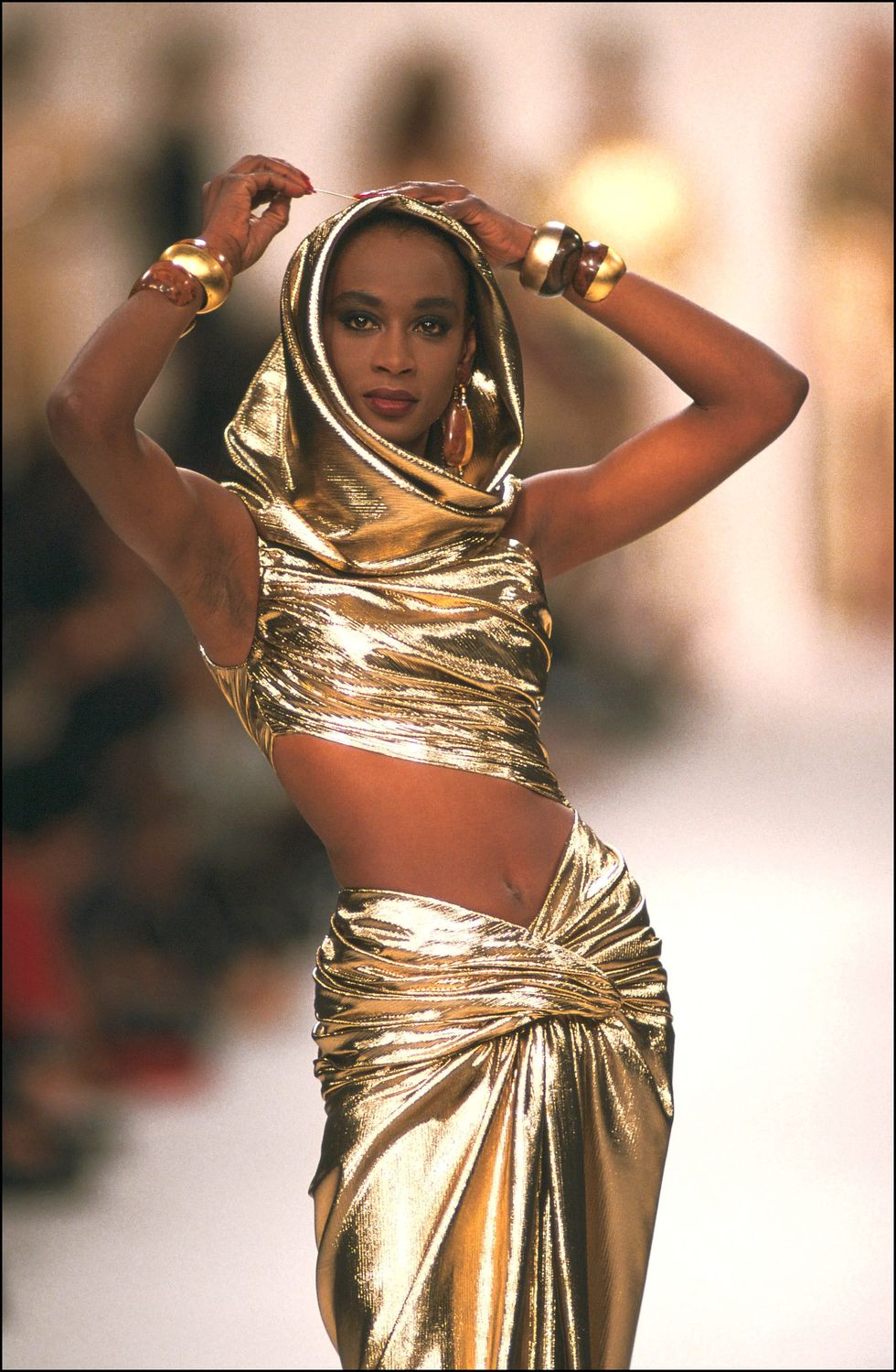 A model wearing a gold Yves Saint Laurent hooded dress. Winter 1992. Miley Cyrus has recently worn this dress in her music video 'Flowers'.