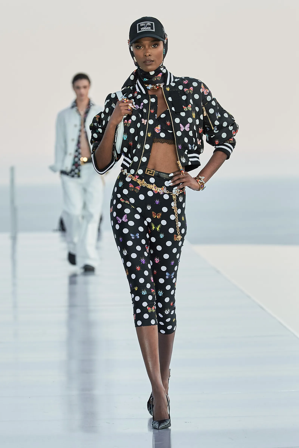 Dua Lipa x Versace La Vacanza polka dot and butterfly pedal pushers, bralette and matching bomber jacket. With a gold chain belt.
