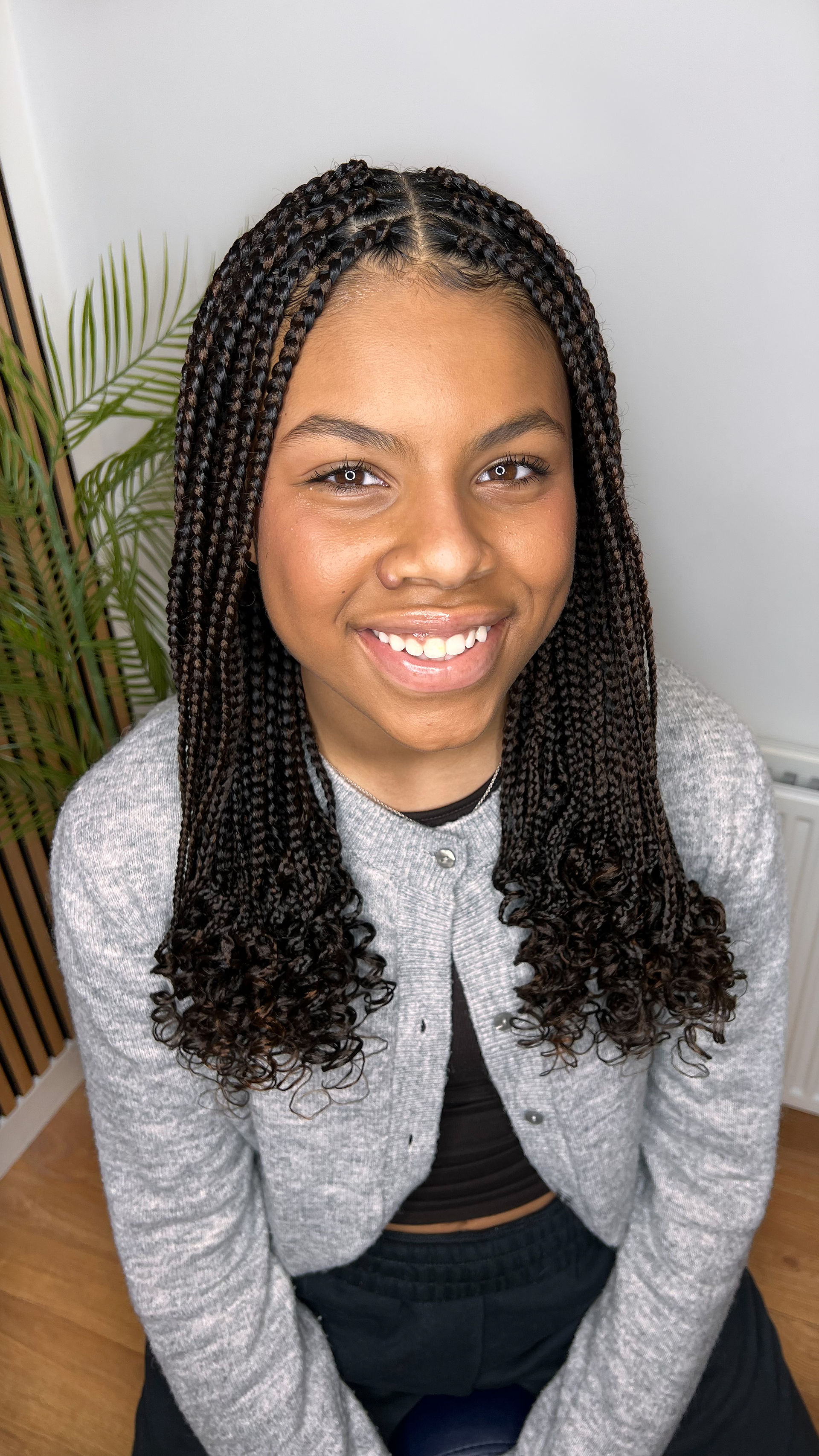 A teenager wearing Medium box braids with curly ends