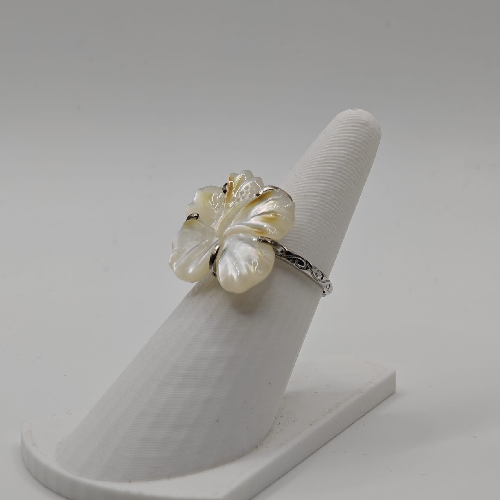 Bague réglable en argent rhodié avec fleur d’hibiscus sculptée en nacre de Tahiti blanche, collection Manava. Vue de Coté
