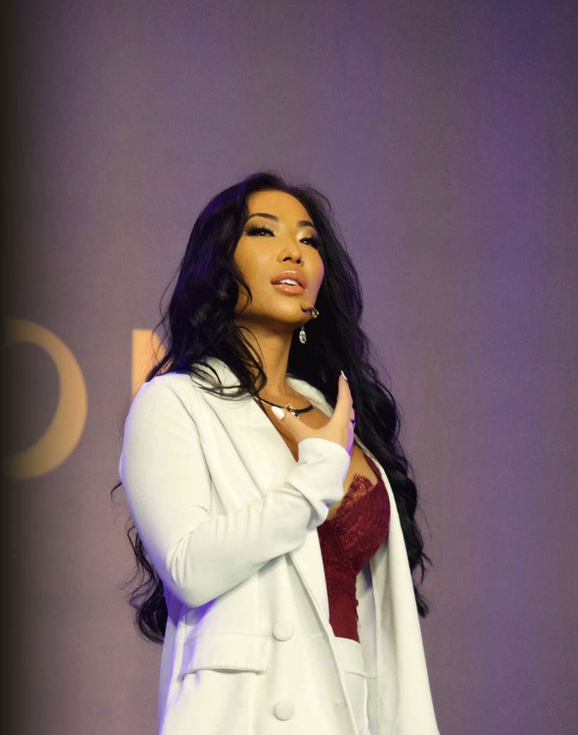 Elisabeth Carson on stage in a white suit, hand on her heart