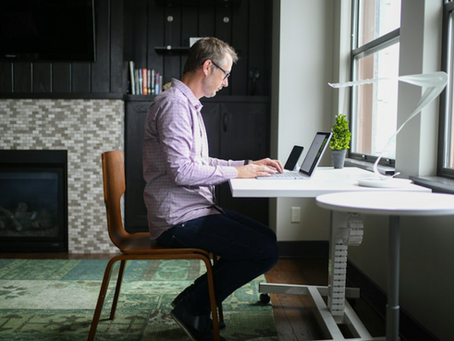 Man sitting at a desk experiencing lower back pain from prolonged sitting