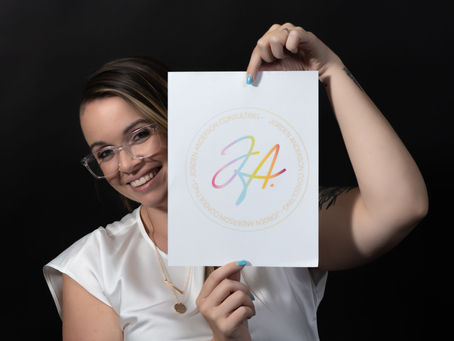 Jorden smiles while holding up a paper featuring her logo. 