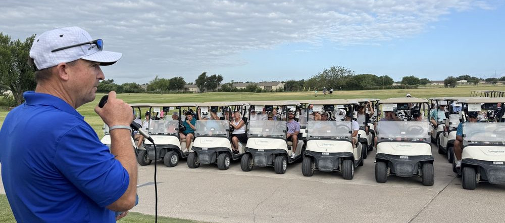 Cole Eason speaks to golfers gathered in golf carts at the Val Eason Memorial Golf Tournament in Bell County, Texas.