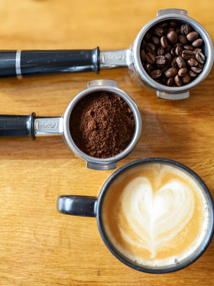 coffee beans, coffee grounds and a latte in a cup