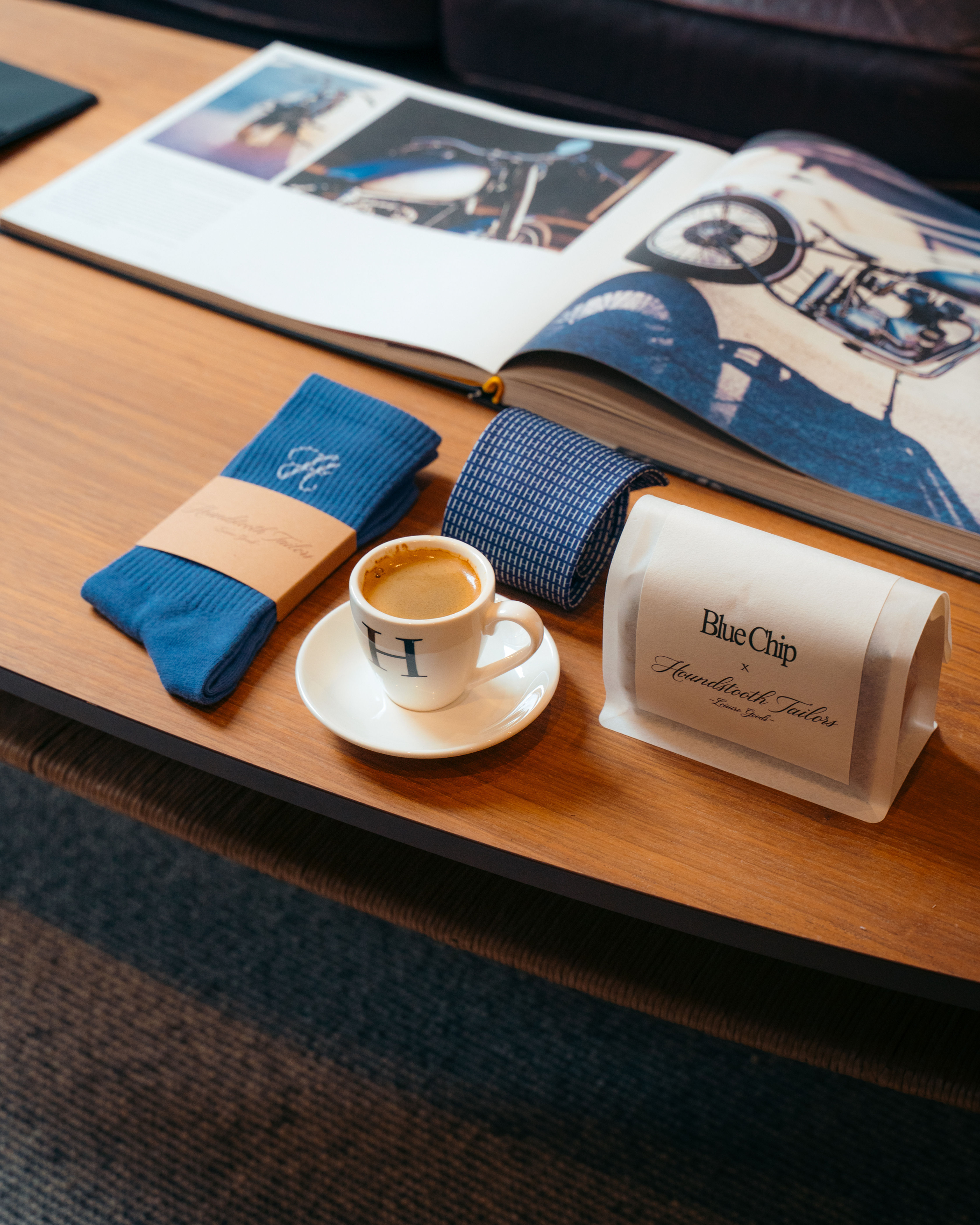 Blue socks, coffee cup with "H", BlueChip label, open book, on table.