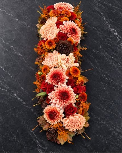 Langwerpig bloemstuk met oranje en rode chrysanten