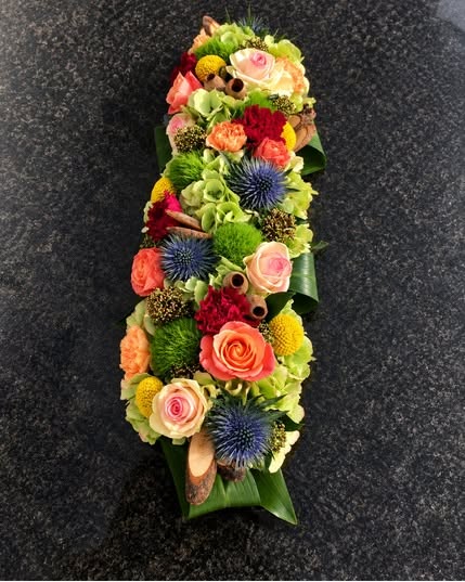 Langwerpig bloemstuk met roze rozen en distels