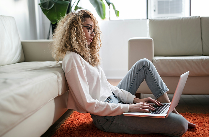 Woman working on laptop at Home, sitting near a sofa
