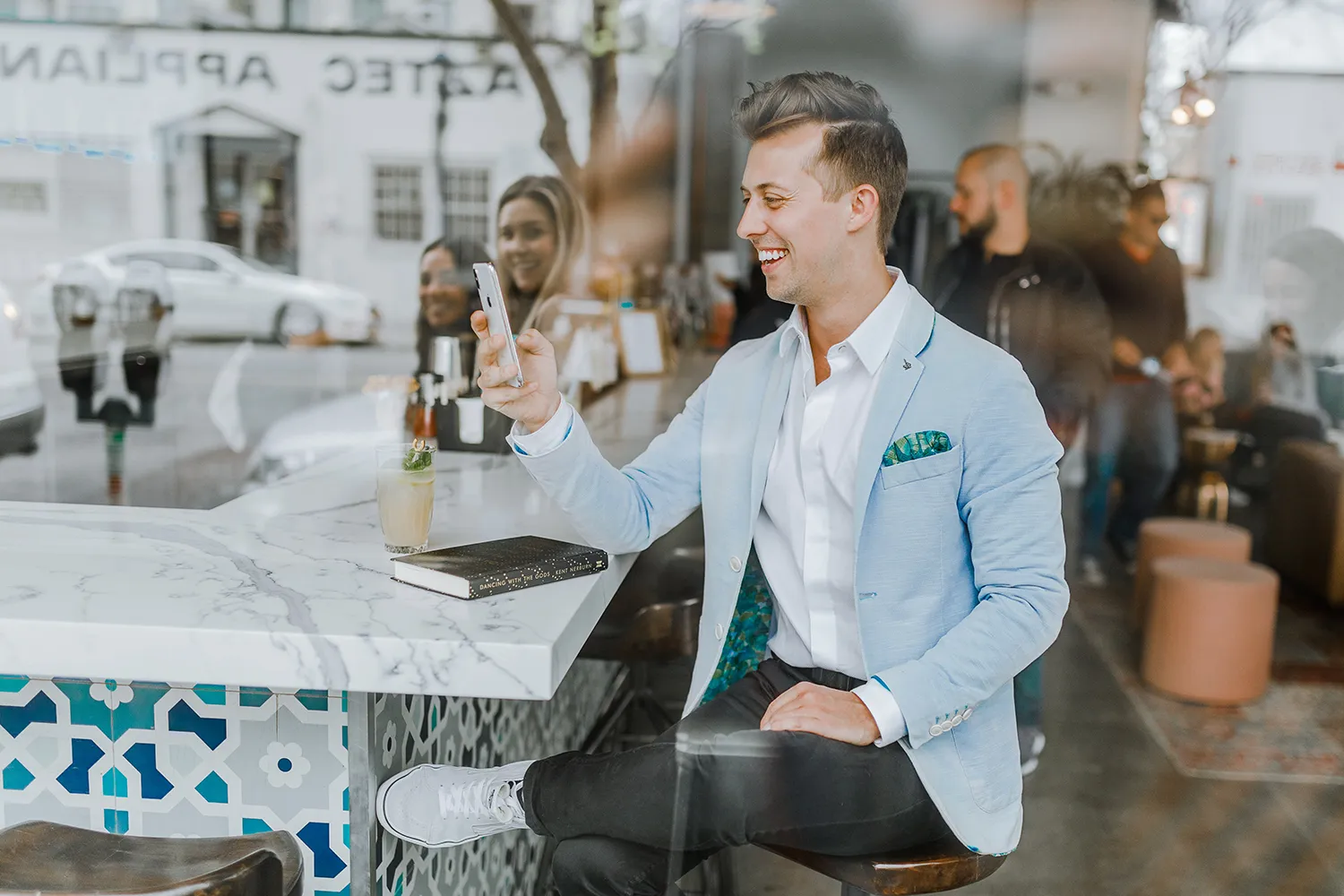 A man sitting at a restaurants, actively on a dating app