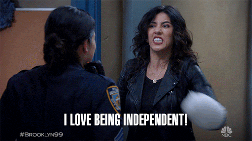 Woman shouting at a police officer in a hallway, holding a white object; caption says I LOVE BEING INDEPENDENT! with Brooklyn Nine-Nine logo