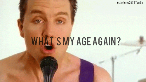 Man singing into a microphone on a white stage, with large text reading WHAT'S MY AGE AGAIN? and a playful, energetic mood