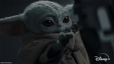 Baby Grogu in a tan robe reaches forward in a dark scene, with Disney+ logo at bottom right.