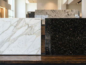 Marble and Granite Difference: A white veined marble slab next to a dark granite slab for kitchen countertop choice.