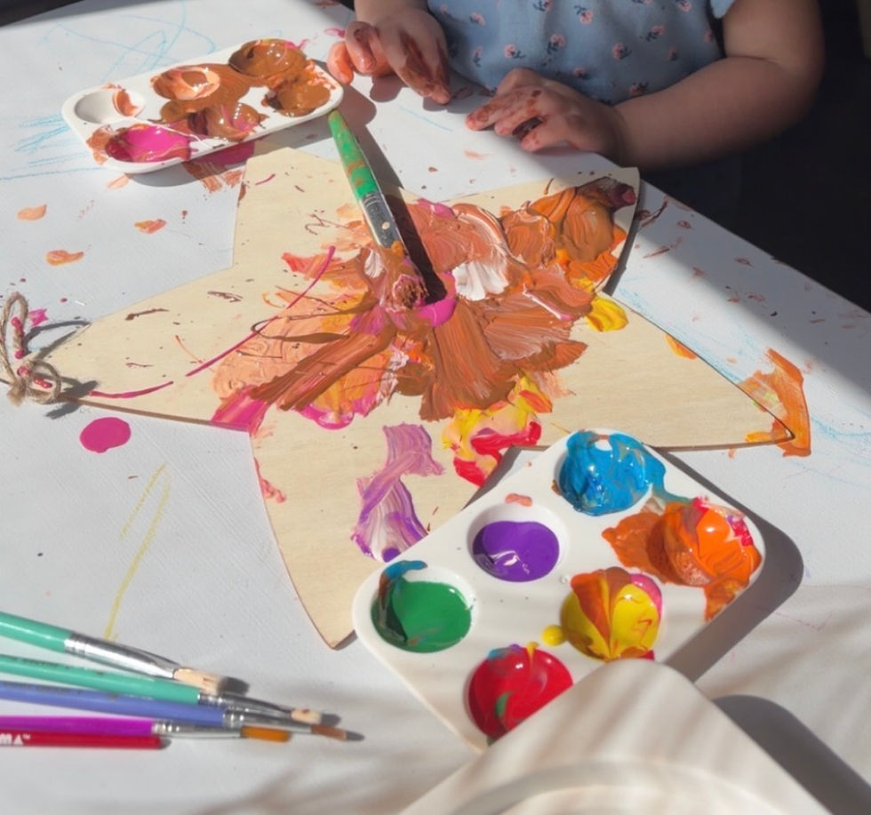 Child painting a wooden star at an event