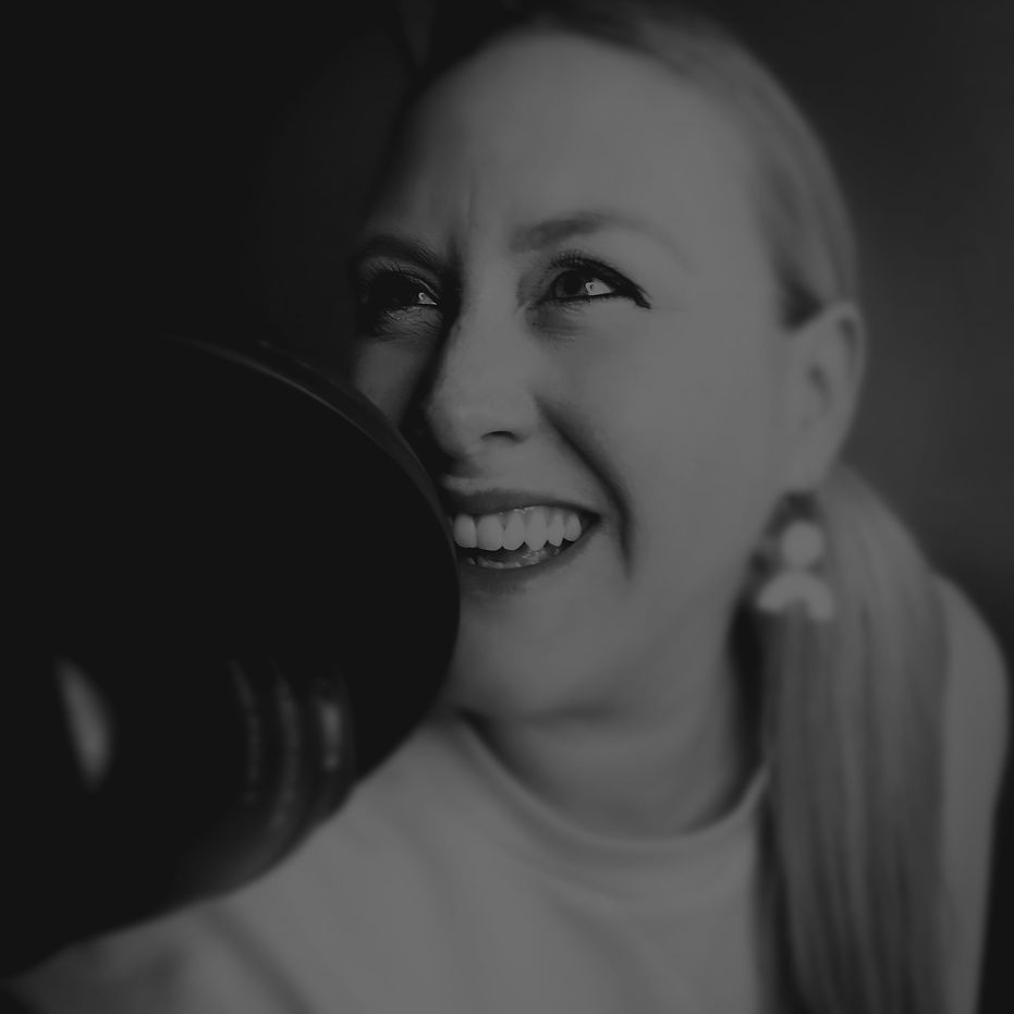 Black and white photo of Liz Hamlet smiling with podcast microphone