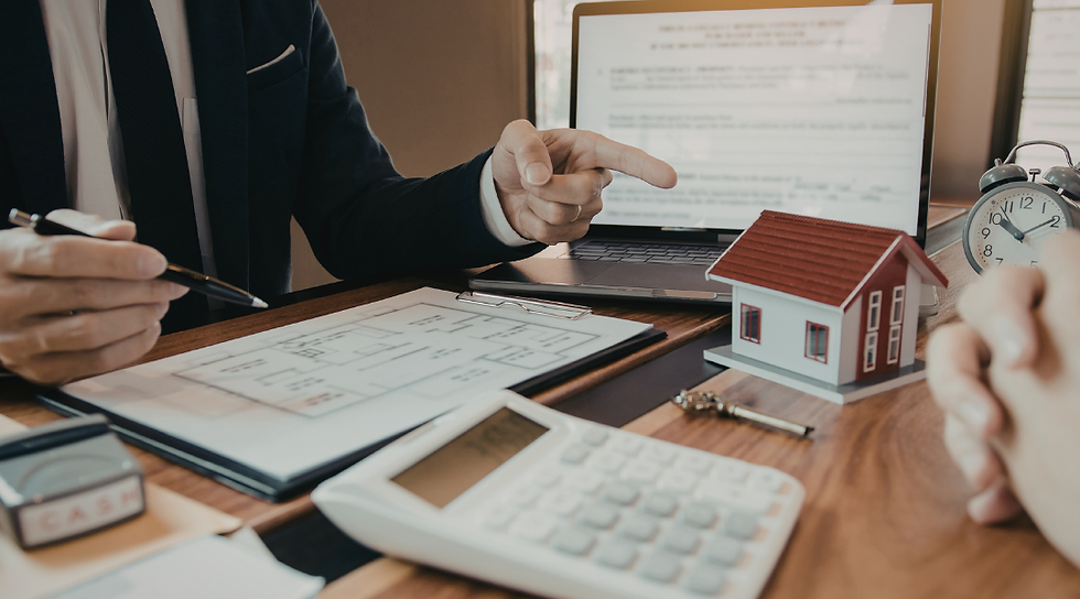 Real estate agent explaining transaction details to a client while reviewing documents with a property model on the desk