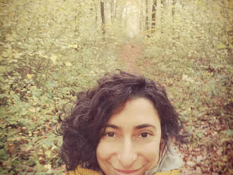 Femme souriante marchant dans une forêt d’automne, symbole d’équilibre, d’écoute et de communication bienveillante.