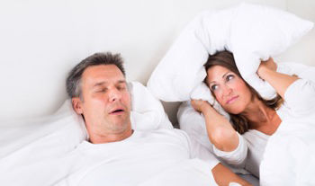 Man Snoring With Woman Holding Pillow To Her Ears.jpg