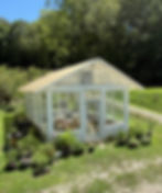 Small white greenhouse near plants for raw sourwood honey.