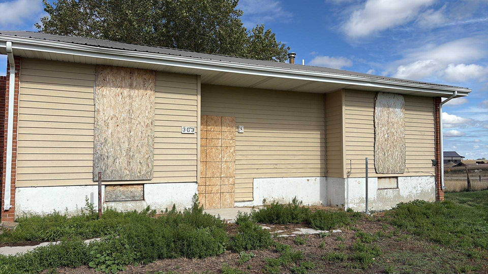 House in poor condition, boarded up.