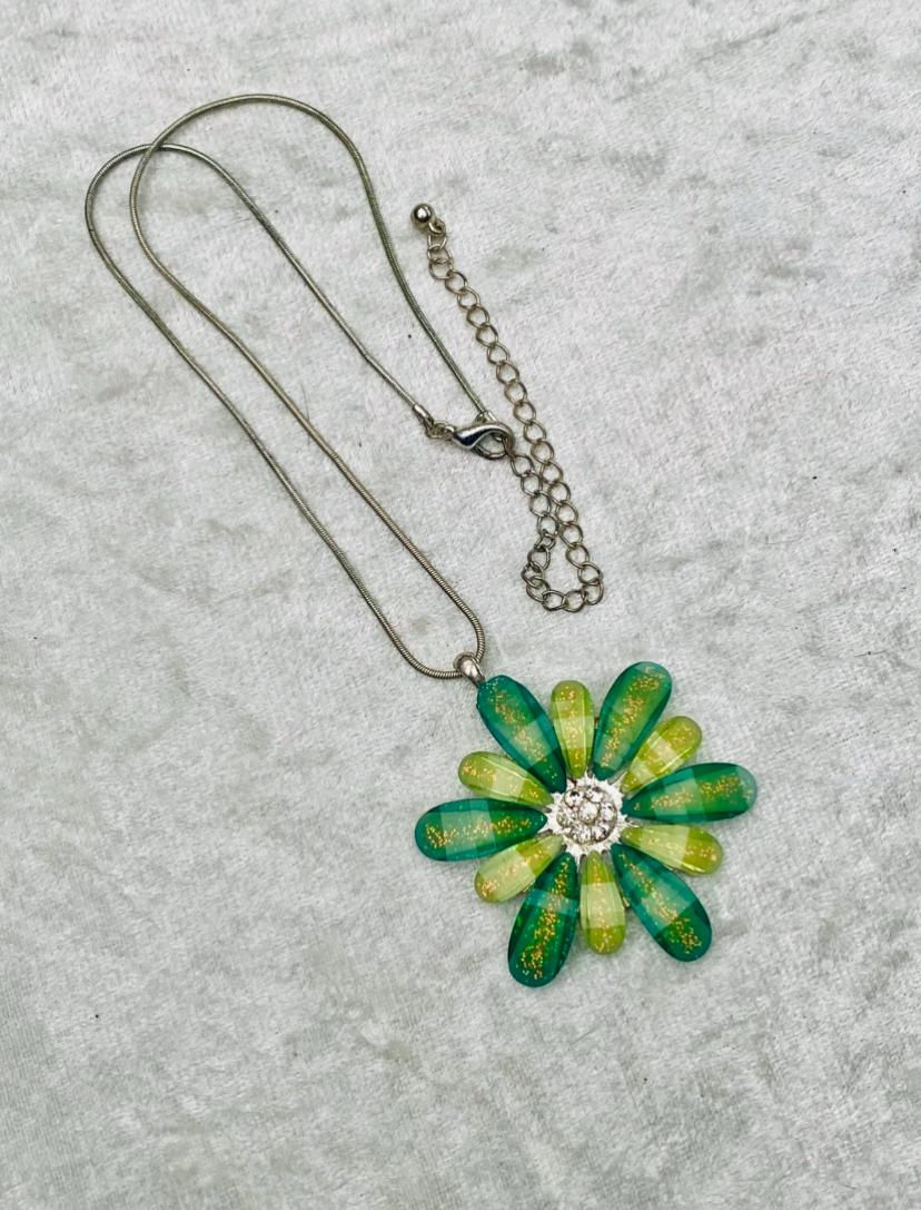 Green and yellow flower pendant necklace on a white surface. Timeless Jewellery