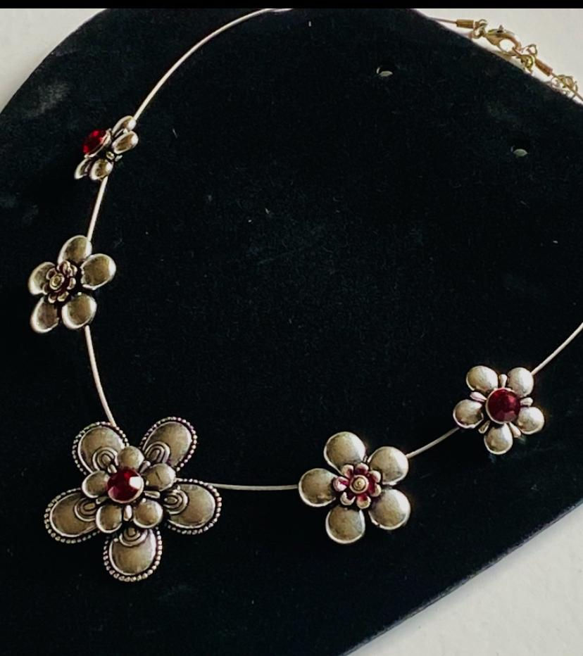 Floral necklace with red jewels on display for Timeless Jewellery.