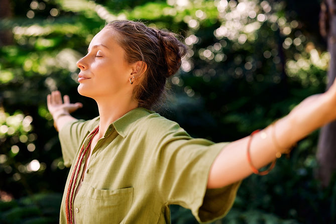 Serene vrouw opent en strekt haar armen met gesloten ogen, omarmt de frisse lucht 