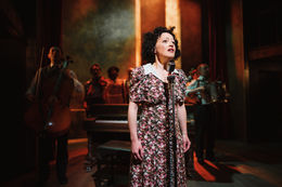 Lighting Programmer London a woman in a floral dress sings into a microphone