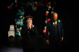 Theatre Lighting Programmer London two men in suits are standing in front of a heart shaped balloon arch
