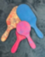 Four colorful paddles arranged, featuring OTK Leather with unique designs.