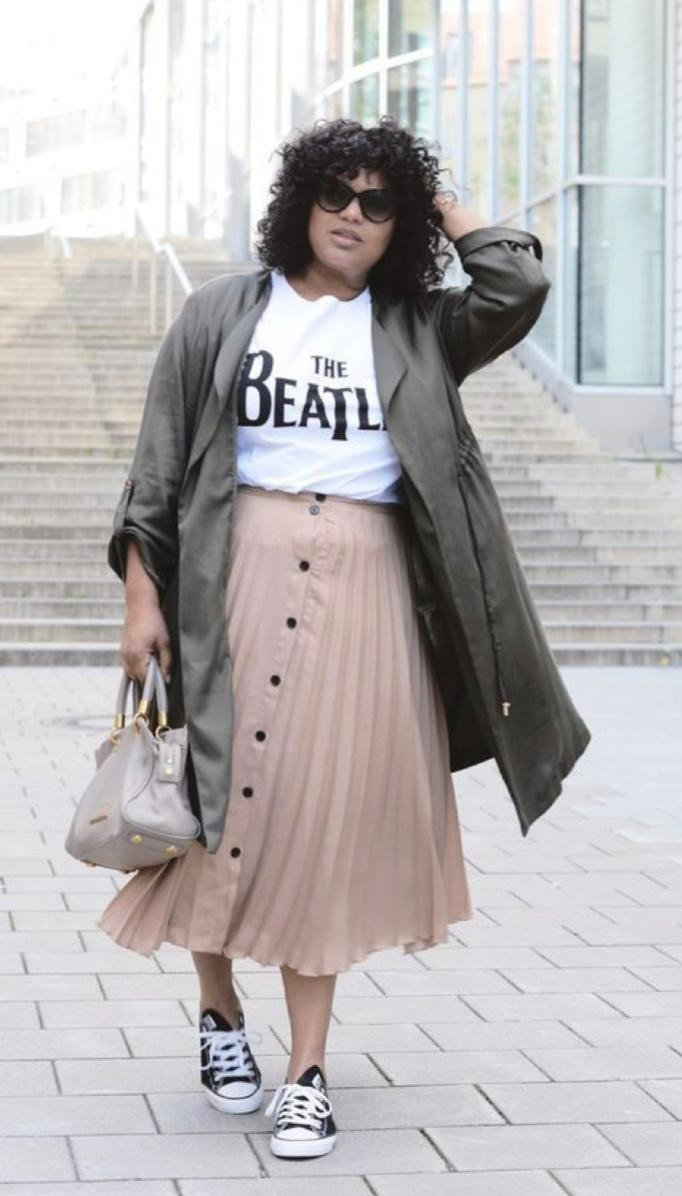 mulher plus size vestindo saia midi rosa e tênis