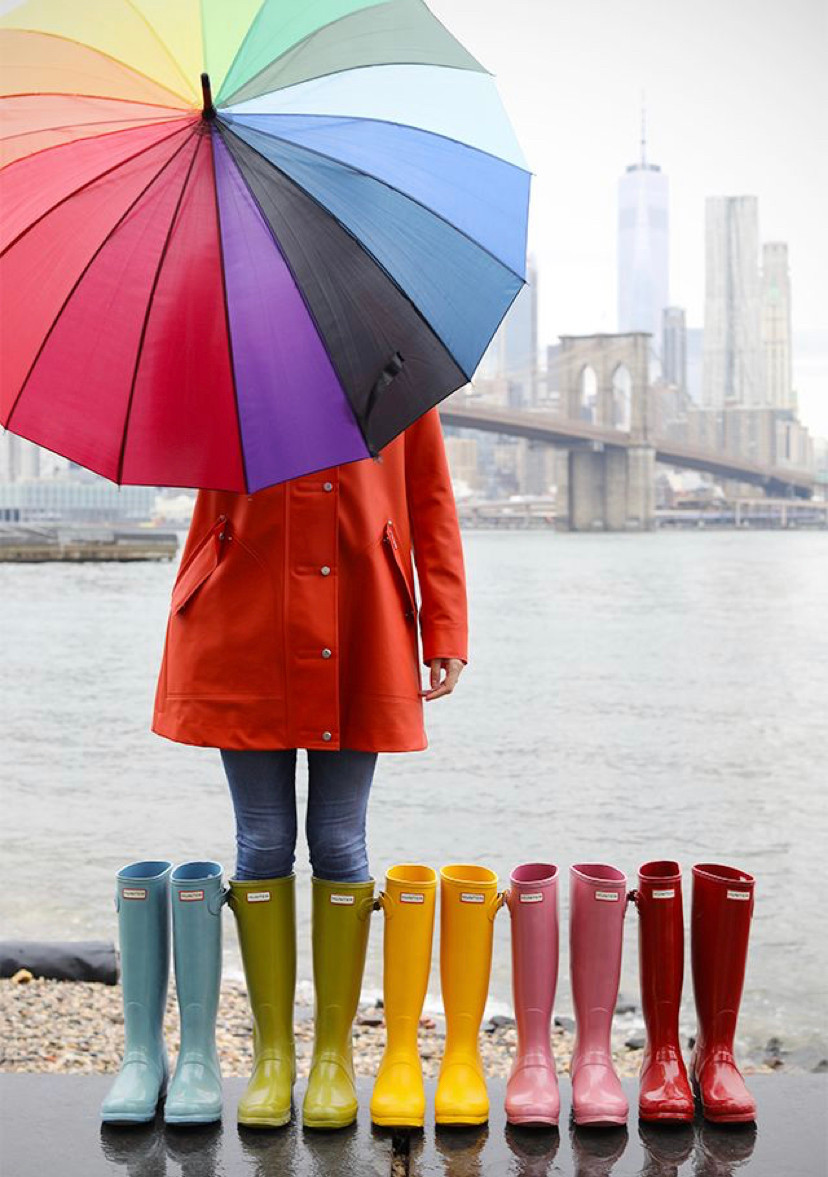 mulher com guarda chuva colorido exibindo botas tipo galocha