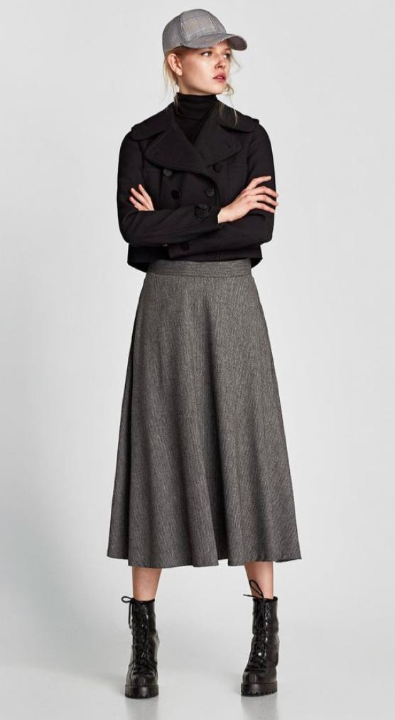 mulher vestida com boné cinza casaco preto e saia midi cinza