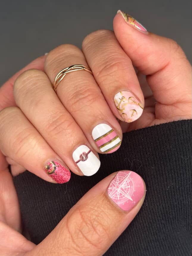 Thumbnail: Model wearing Dockside Glam pink and gold nautical nail wraps with glitter, anchors, rope stripes, and starfish accents.
