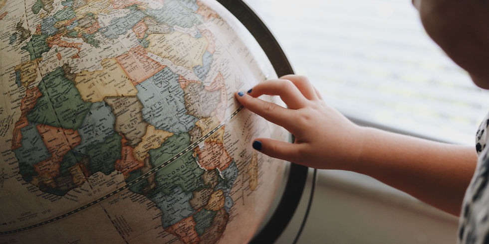 Main d’un enfant posée sur un globe terrestre représentant le tour du monde