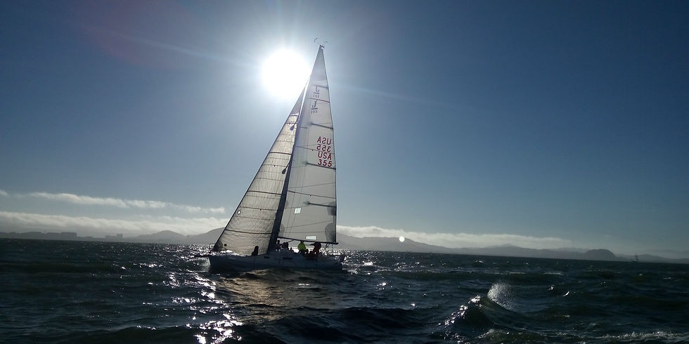Voilier de course naviguant en pleine mer sous un ciel lumineux