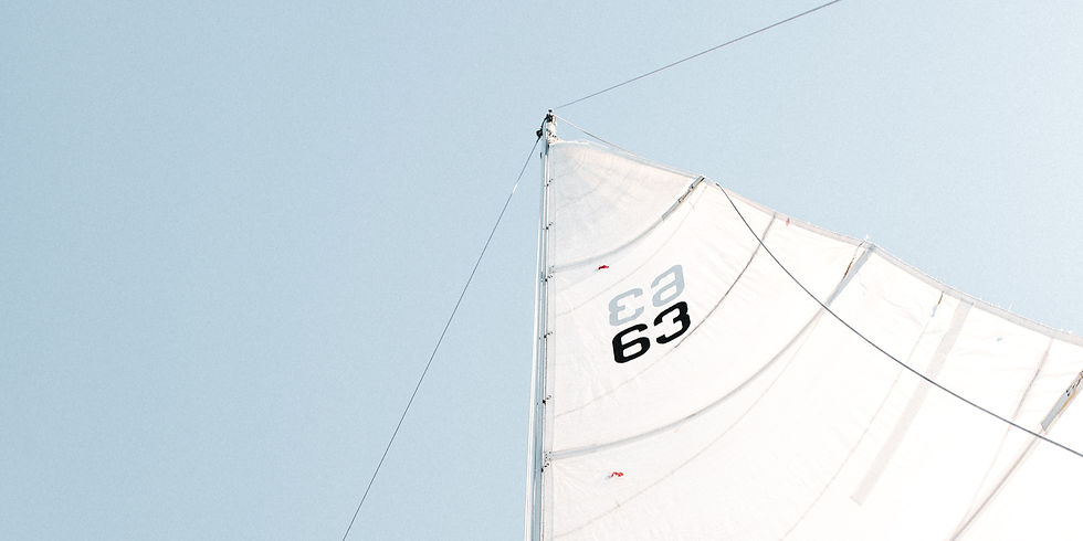 Détail d’une voile blanche hissée sur le mât d’un voilier sous un ciel clair