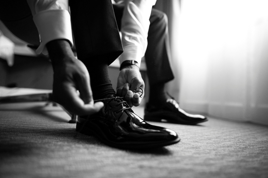 Groom wearing his shoes during the groom prep
