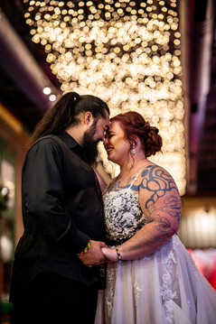 Bridgewood resort winter wedding, bride and groom hold hands and smile at each other.  white christmas lights are blurred in the background