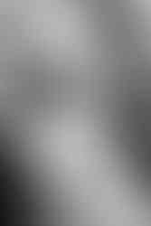 Close up black and white photo of man and woman about to kiss. Woman's wedding ring is visible on hand resting lightly on grooms neck.