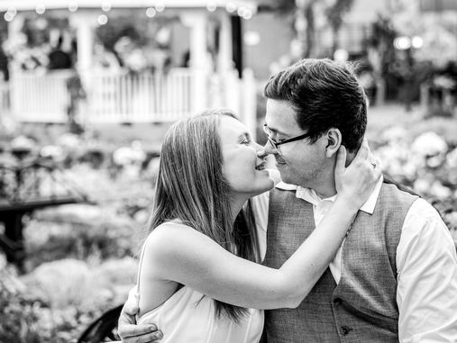 black and white photo of an engaged couple sitting close together and about to kiss at the Mitchell park domes in milwaukee