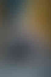 a couple leans in for a kiss while sitting in front of a brick building with their dog