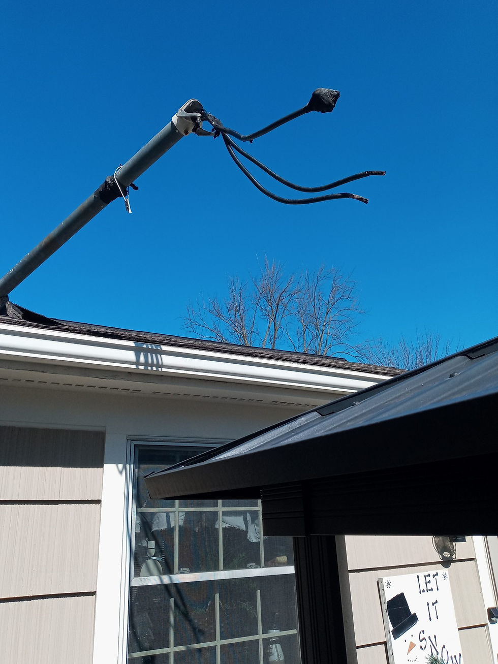 Overhead service mast with the utility drop wires attached at the roofline of a house