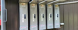 Five numbered 200-amp disconnects in a row on a brown metal building, each with a 3D Electric sticker