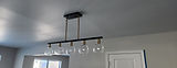 Black and brass linear pendant with five glass globe shades in a freshly painted room